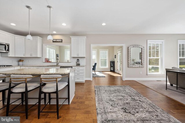 kitchen with light stone countertops, a breakfast bar, white cabinets, and a kitchen island