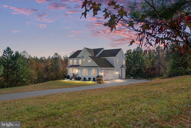 front facade with a garage and a lawn