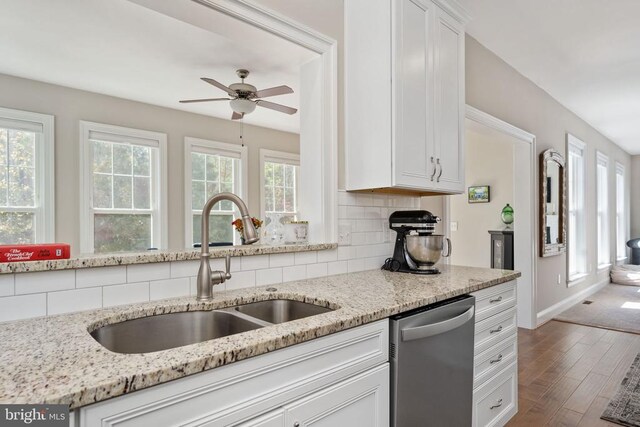 kitchen with dishwasher, sink, light stone countertops, and white cabinets