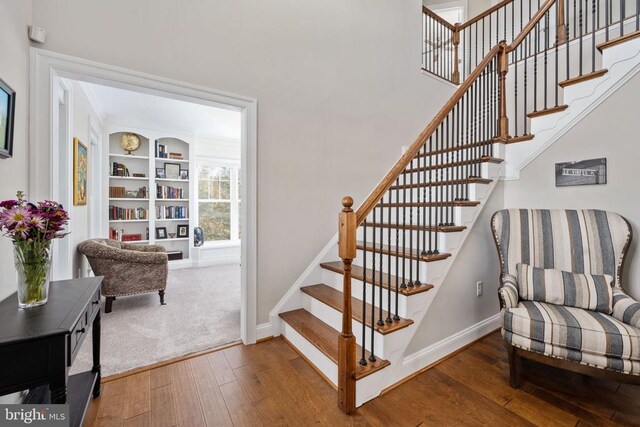 stairs featuring hardwood / wood-style flooring and built in shelves