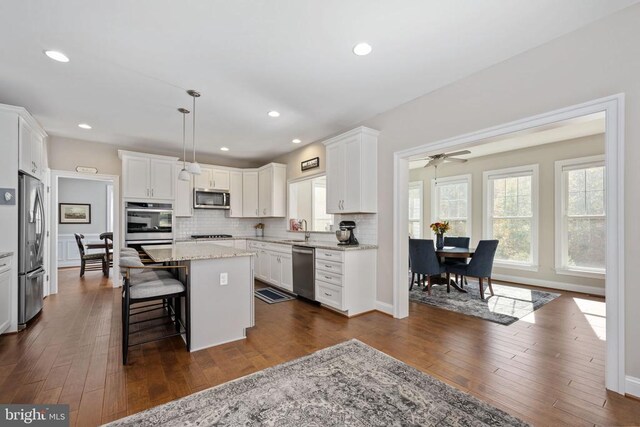 kitchen with appliances with stainless steel finishes, decorative light fixtures, a center island, and white cabinets