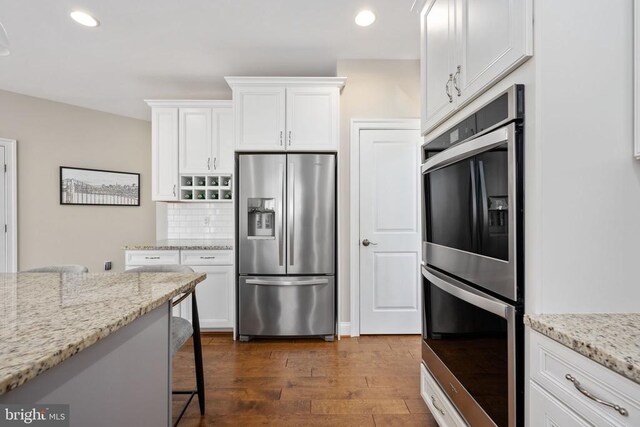 kitchen featuring light stone counters, appliances with stainless steel finishes, and white cabinets