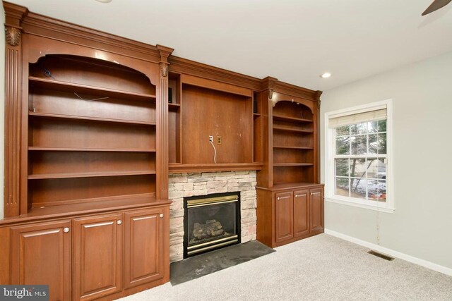 unfurnished living room with carpet flooring and a stone fireplace