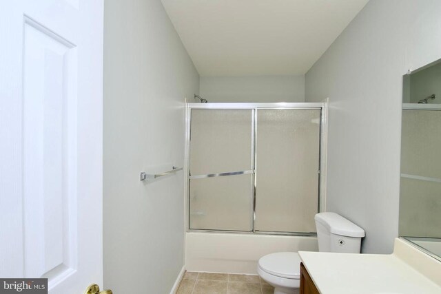 full bathroom with bath / shower combo with glass door, vanity, toilet, and tile patterned flooring