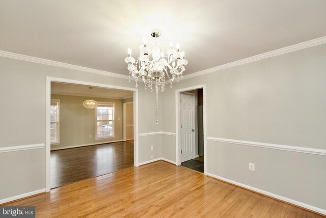 unfurnished dining area with hardwood / wood-style flooring, crown molding, and a chandelier