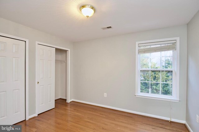 unfurnished bedroom featuring multiple closets and light wood-type flooring