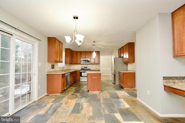 kitchen featuring light stone counters, decorative light fixtures, a center island, a notable chandelier, and stainless steel appliances