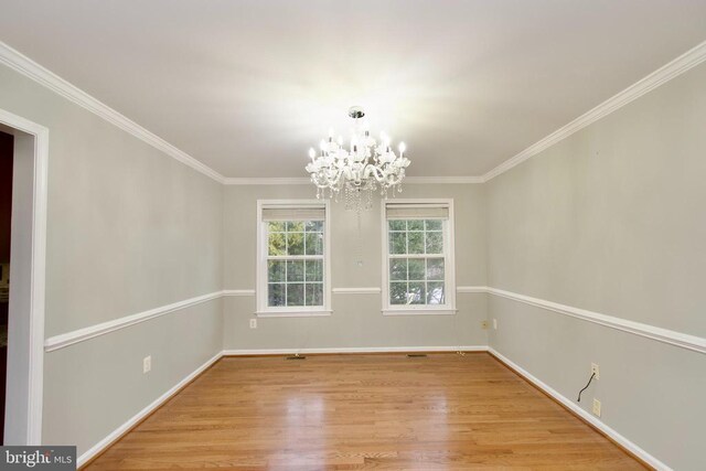 empty room featuring ornamental molding, light hardwood / wood-style flooring, and a notable chandelier