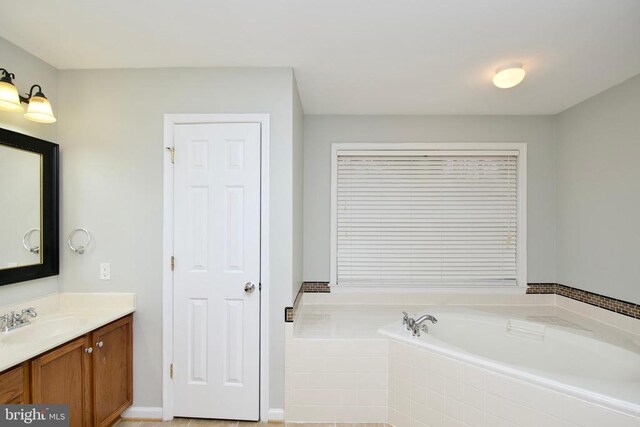 bathroom featuring tiled tub and vanity