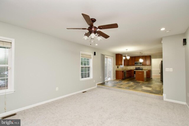 unfurnished living room featuring ceiling fan and dark colored carpet