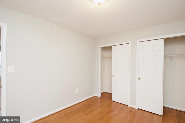 unfurnished bedroom with multiple closets and wood-type flooring