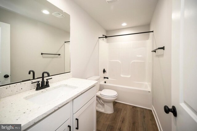 full bathroom with vanity, hardwood / wood-style floors, washtub / shower combination, and toilet