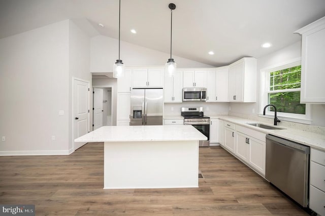 kitchen featuring stainless steel appliances, white cabinetry, a center island, and sink