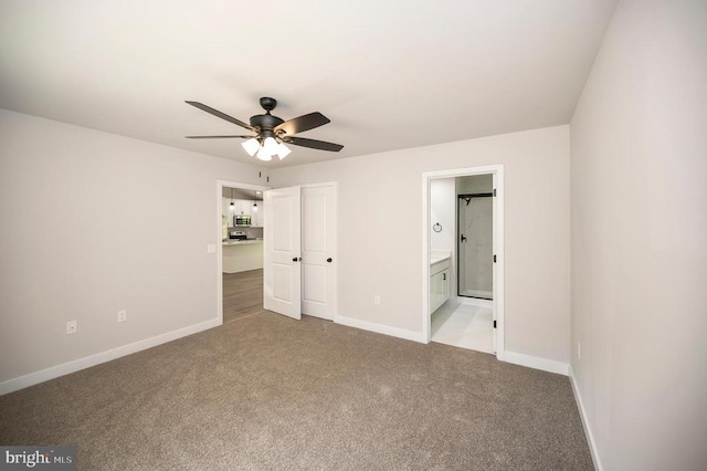 unfurnished bedroom featuring ensuite bath, light colored carpet, and ceiling fan