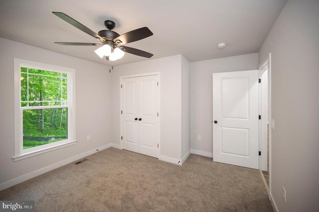 unfurnished bedroom featuring light carpet, a closet, and ceiling fan