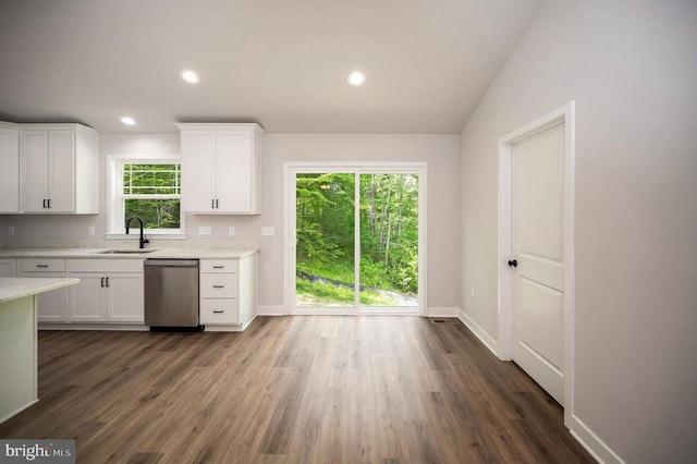 kitchen with sink, white cabinets, dark hardwood / wood-style flooring, stainless steel dishwasher, and light stone counters