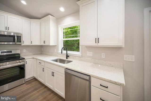 kitchen with sink, appliances with stainless steel finishes, dark hardwood / wood-style floors, light stone countertops, and white cabinets