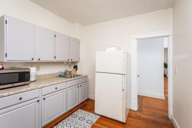 kitchen with sink, light hardwood / wood-style floors, and white fridge