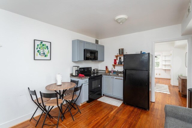 kitchen with dark hardwood / wood-style floors, gray cabinets, sink, and black appliances