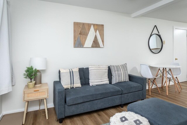 living room with dark hardwood / wood-style flooring and beamed ceiling