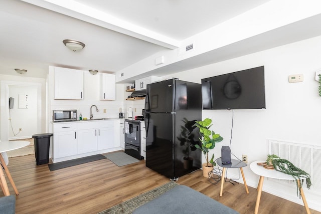 kitchen with tasteful backsplash, white cabinetry, sink, black appliances, and dark wood-type flooring