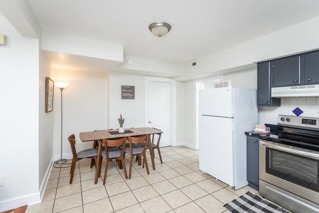 kitchen featuring light tile patterned flooring, blue cabinets, decorative backsplash, white fridge, and electric range