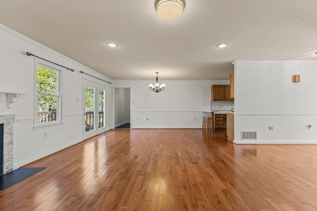 unfurnished living room with a high end fireplace, visible vents, light wood finished floors, and crown molding