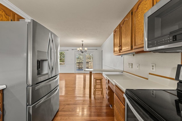 kitchen with a notable chandelier, brown cabinets, light wood finished floors, and stainless steel appliances