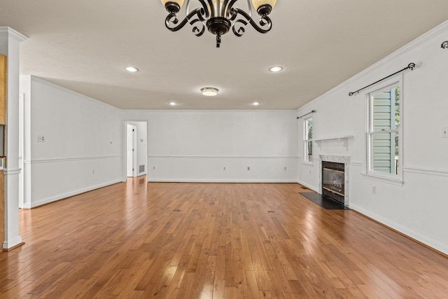 unfurnished living room with light wood-style flooring, crown molding, baseboards, and a premium fireplace