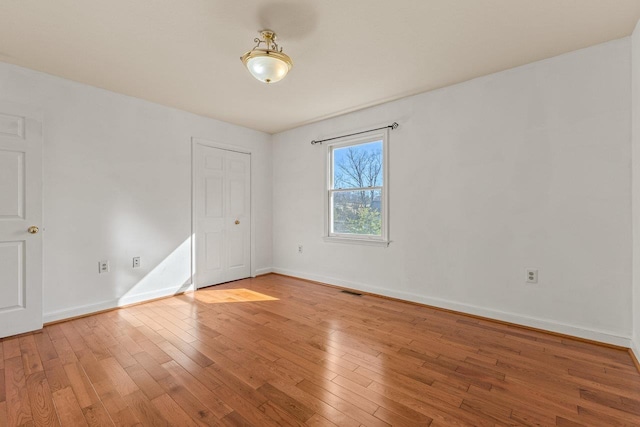 empty room featuring visible vents, baseboards, and light wood finished floors