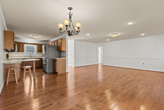 kitchen with open floor plan, freestanding refrigerator, brown cabinetry, light countertops, and dark wood-style flooring