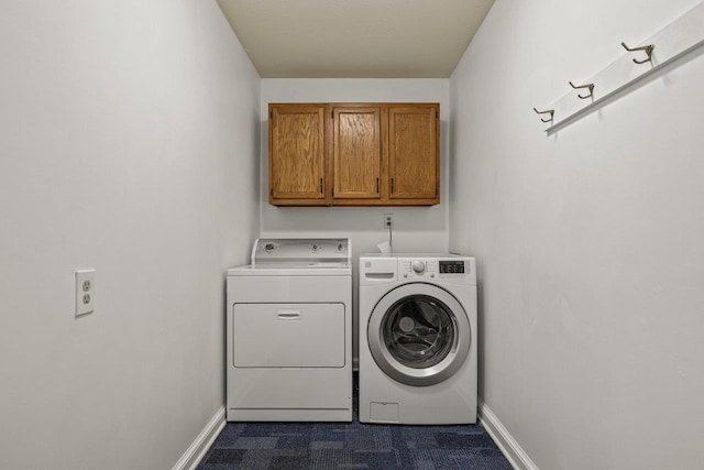 clothes washing area featuring washing machine and clothes dryer, cabinet space, and baseboards