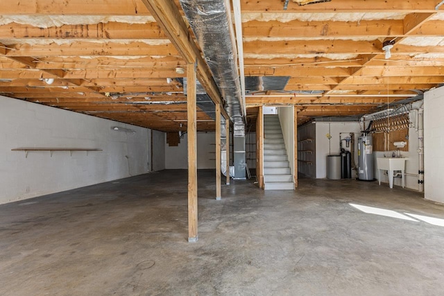 unfinished basement with a sink, stairs, and water heater