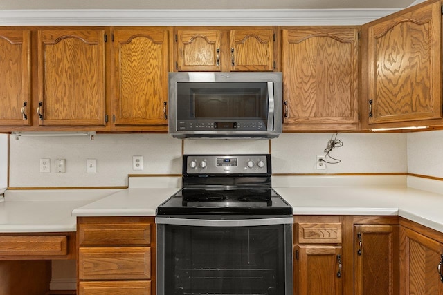 kitchen featuring stainless steel microwave, light countertops, brown cabinets, and range with electric stovetop