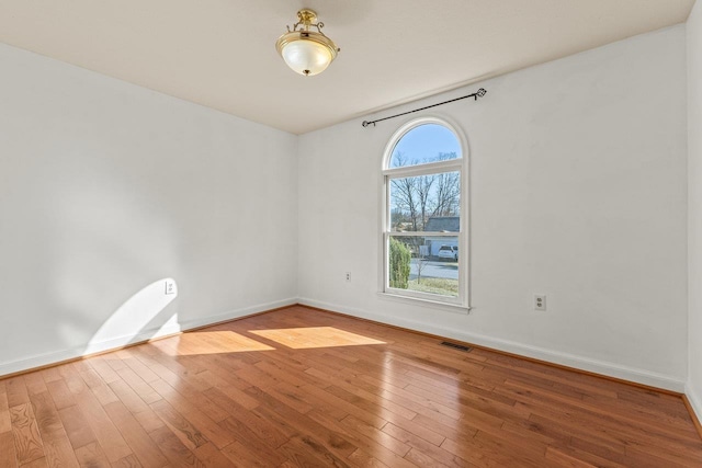 spare room with visible vents, baseboards, and wood-type flooring