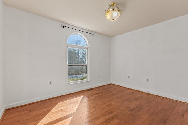 unfurnished room with visible vents, baseboards, and wood-type flooring