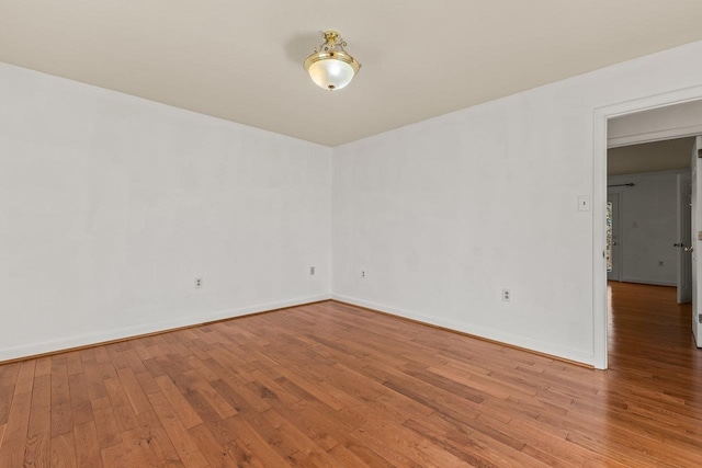 unfurnished room featuring hardwood / wood-style floors and baseboards