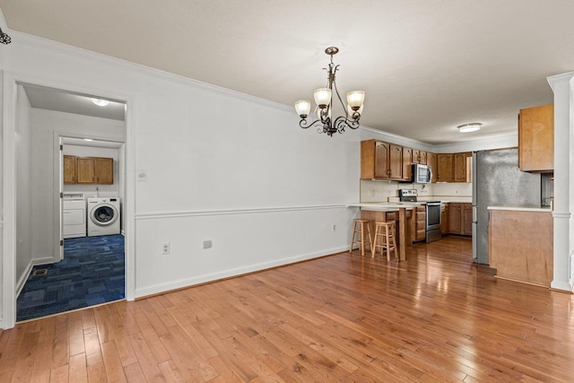 kitchen featuring washer and clothes dryer, appliances with stainless steel finishes, crown molding, light countertops, and brown cabinetry