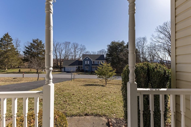 view of yard with aphalt driveway and a porch