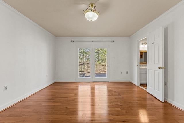 empty room with crown molding, baseboards, and wood-type flooring