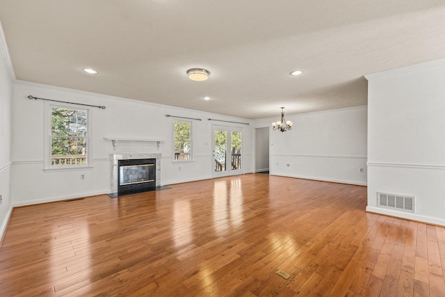 unfurnished living room with light wood finished floors, visible vents, a high end fireplace, and ornamental molding