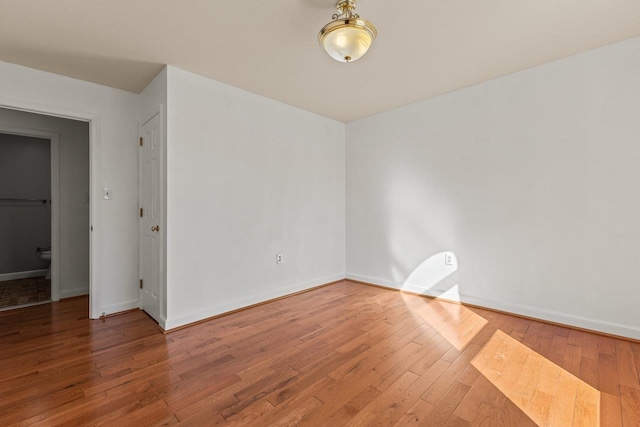 unfurnished room featuring hardwood / wood-style floors and baseboards