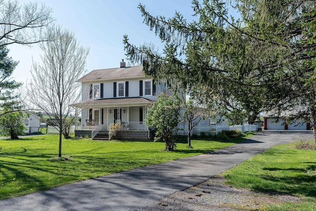 view of front of home featuring a garage, a front yard, and covered porch