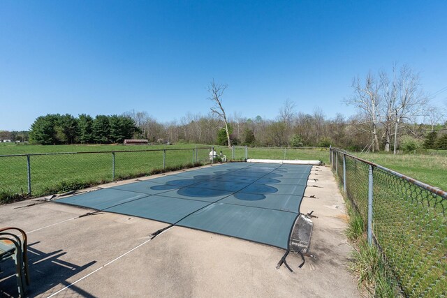 view of pool with basketball hoop and a lawn