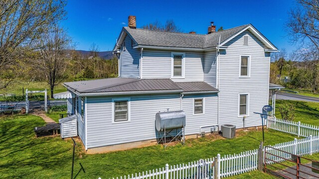 back of property with a yard and central AC