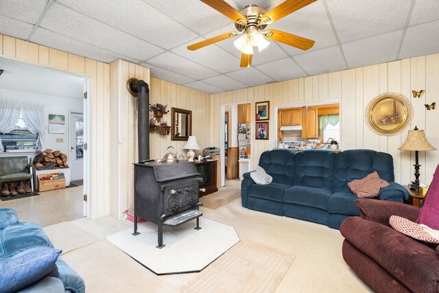 living room with a wood stove, a drop ceiling, and ceiling fan