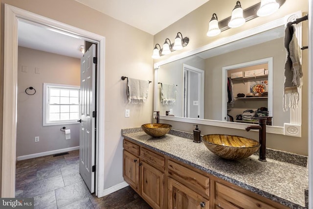 bathroom with visible vents, stone finish flooring, vanity, and baseboards