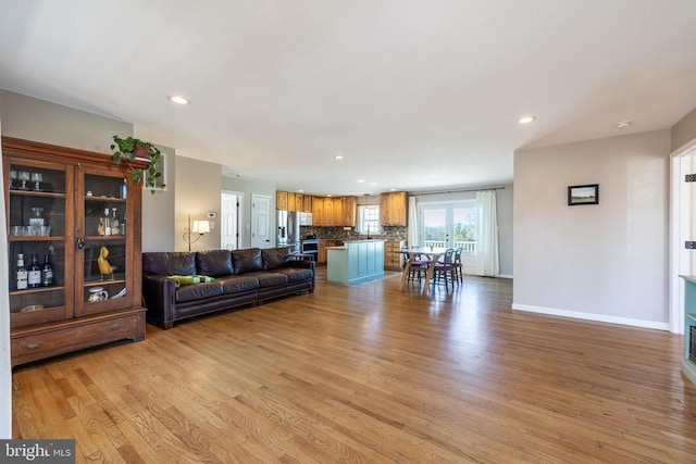 unfurnished living room with recessed lighting, light wood-style flooring, and baseboards