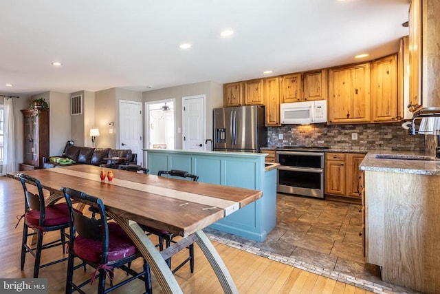 kitchen featuring a center island, stainless steel appliances, tasteful backsplash, light countertops, and open floor plan