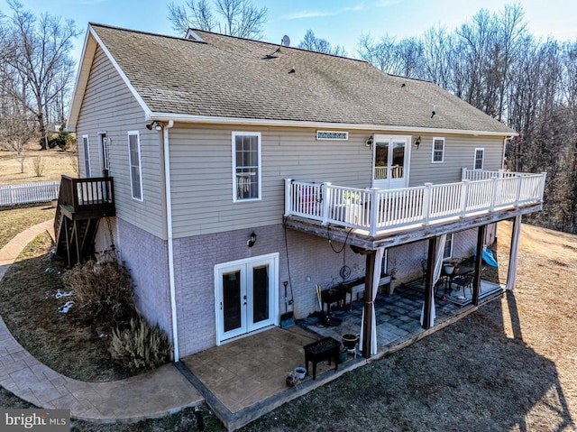 back of house with a patio area, roof with shingles, brick siding, and french doors